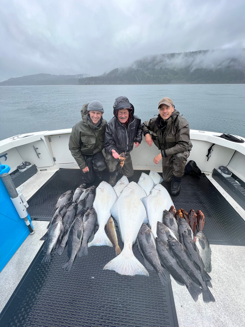 Three men in front of their large catch of fish.