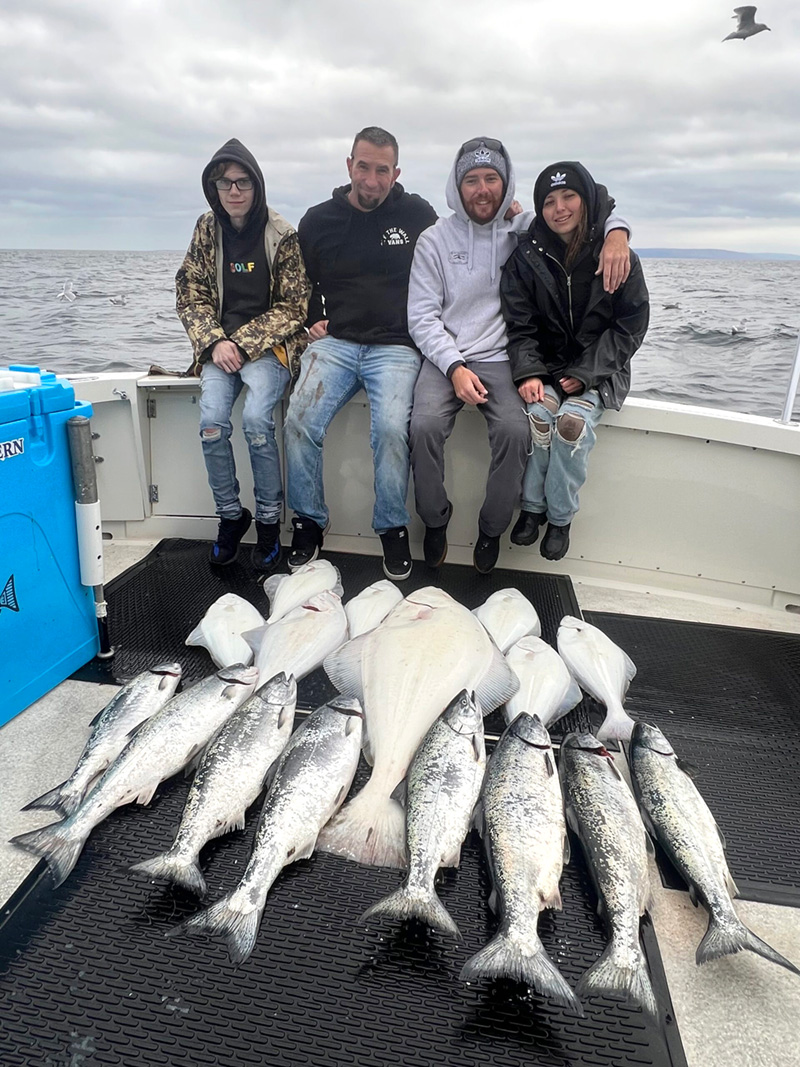 Four fishermen sit behind their catch of fish.