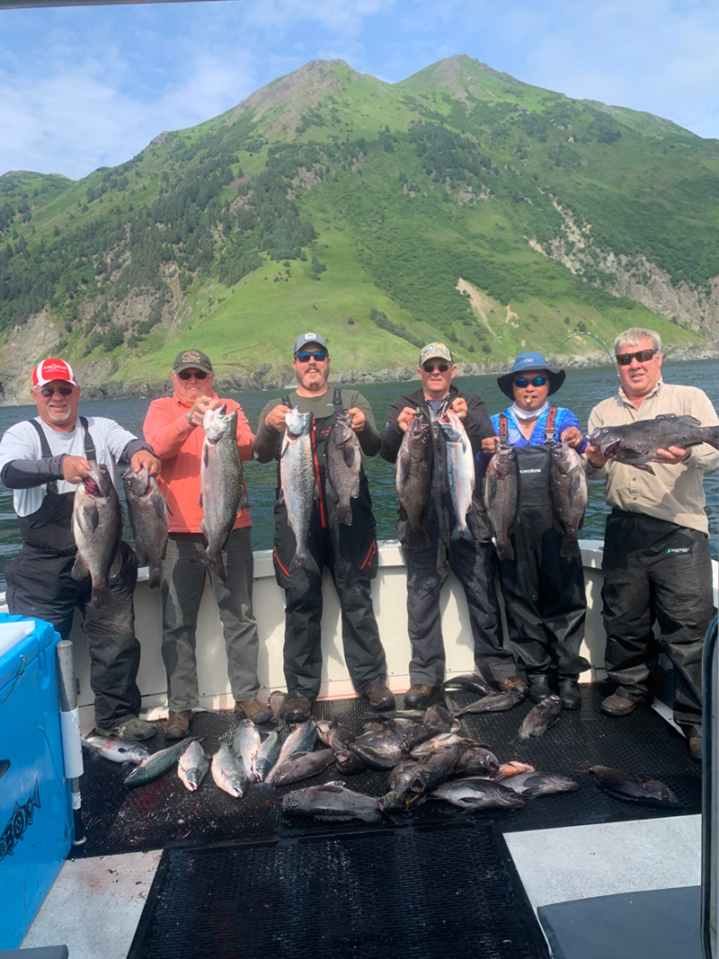 Six fishermen hold up two fish each behind their catch.